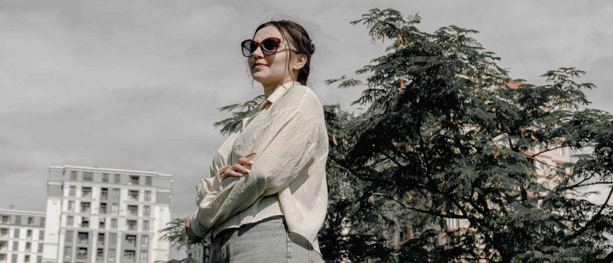 Street style: женщина в кремовой рубашке и джинсах на фоне города