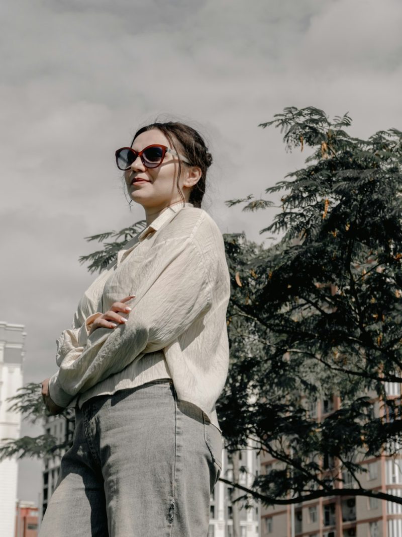 Street style: женщина в кремовой рубашке и джинсах на фоне города
