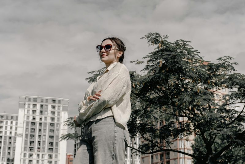 Street style: женщина в кремовой рубашке и джинсах на фоне города