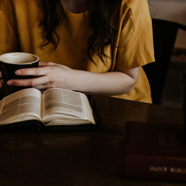 Женщина с кружкой и раскрытой книгой в тёплом свете