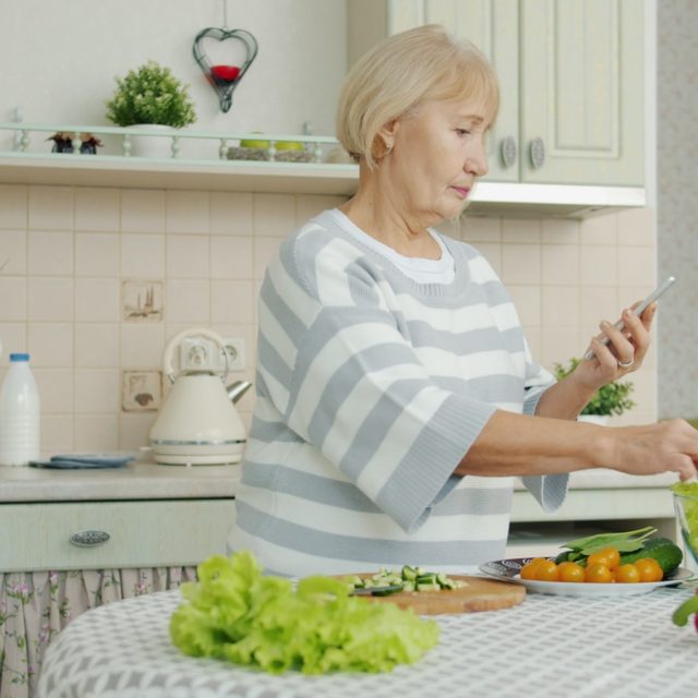 Elderly woman preparing salad in a kitchen