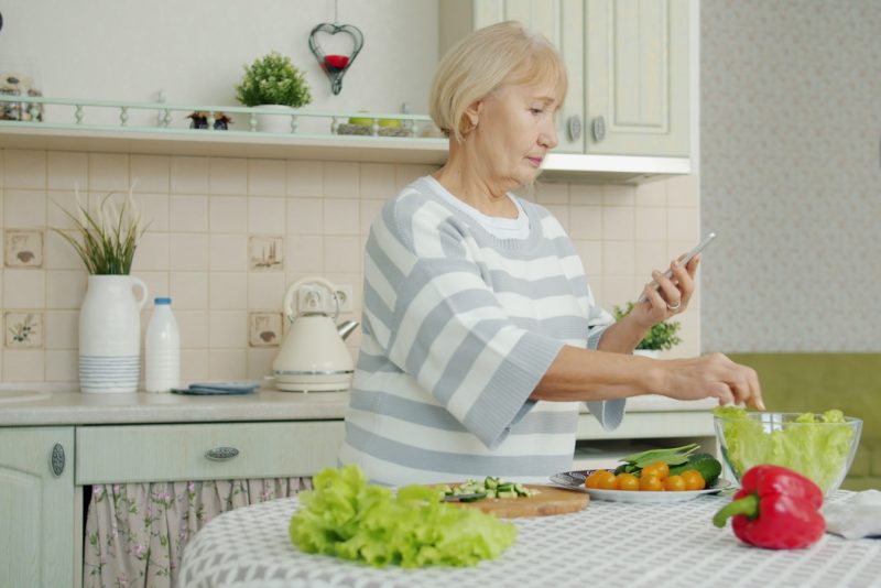 Elderly woman preparing salad in a kitchen