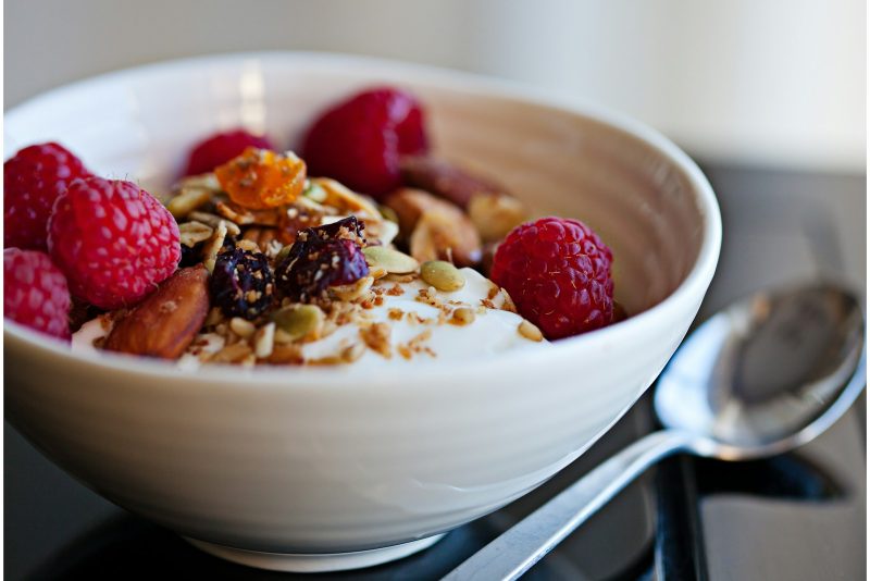 a bowl of granola with raspberries and nuts