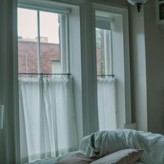 a bed with a white comforter and pillows in front of a window