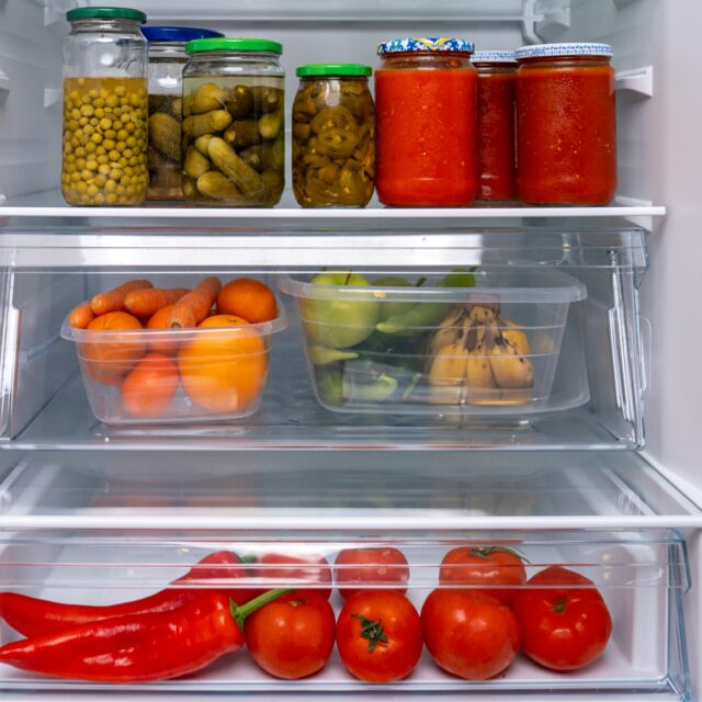 Открытый холодильник с банками и контейнерами овощей на полках